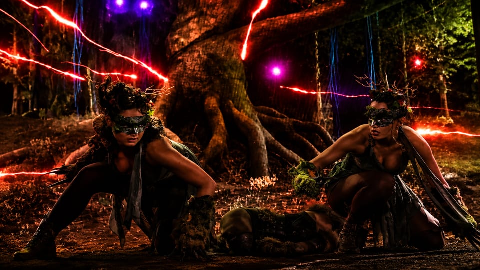 Deux créatures de la forêt devant l'écran LED géant, traversé de traînées de lumière